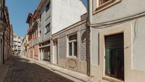 Een geplaveid straatje omzoomd door gebouwen, waarvan sommige betegelde gevels hebben en andere een eenvoudige muur.