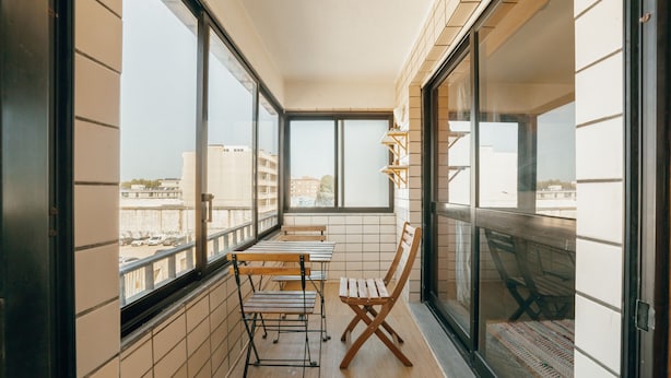 Un balcón con vistas a la ciudad, una mesa con sillas y una silla de madera.