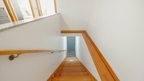Una escalera de madera con barandilla, que lleva a una puerta en la parte superior.