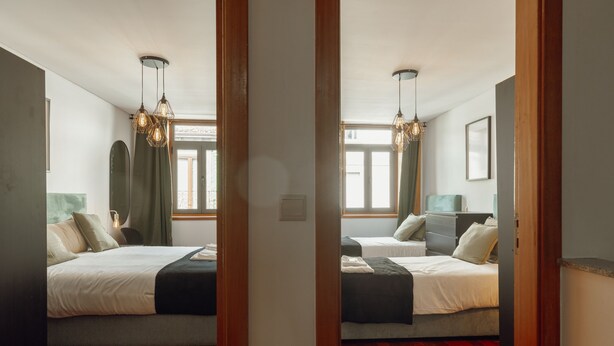 Un dormitorio con dos camas, piso de madera y un ventanal grande.