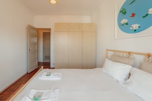 A hotel room with a bed, a wardrobe, and a wall with a floral painting. - Santa Catarina Flat 2BD With Balcony by Vacationy (Porto)
