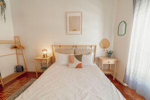 A neatly arranged bedroom with a large bed, bedside tables with lamps, a hanging plant, and a framed picture on the wall. - Santa Catarina Flat 2BD With Balcony by Vacationy (Porto)