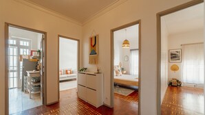 A spacious living area with a patterned wooden floor, a sofa, a coffee table, and a dining table with chairs. There is a kitchen area with a refrigerator and a sink. - Santa Catarina Flat 2BD With Balcony by Vacationy (Porto)