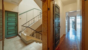 A staircase with a green door and a marble floor leading to a hallway with a patterned floor. - Santa Catarina Flat 2BD With Balcony by Vacationy (Porto)