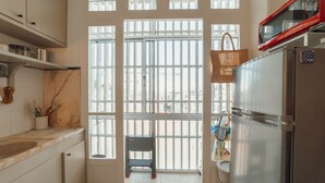 A kitchen with a large window, a refrigerator, and a small stool. - Santa Catarina Flat 2BD With Balcony by Vacationy (Porto)