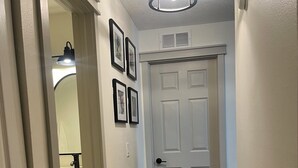 A hallway with a white door, framed pictures on the wall, and a ceiling light fixture. - Near Clearwater Tampa Serene 3-bedroom house with Hot Tub in charming Oldsmar (Oldsmar)