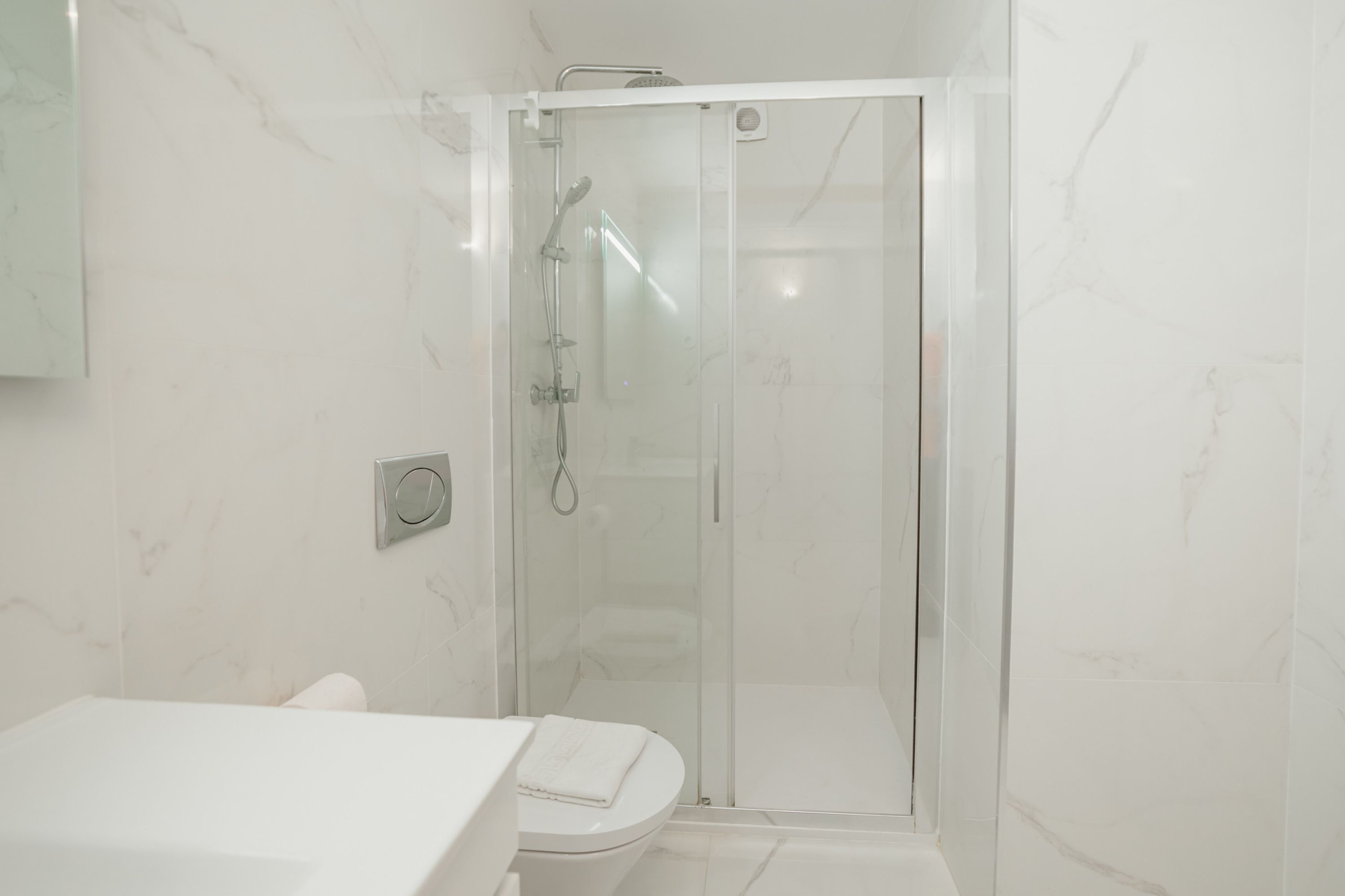 A modern bathroom with a glass-enclosed shower, a toilet, and a sink.
