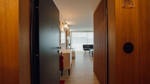A hallway with a wooden door, a desk with a computer, and a chair.