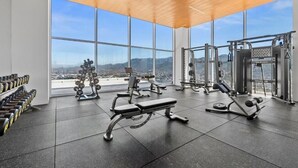 A gym with large windows, weight machines, and dumbbells. - Beachfront Studio,  New & Cozy,   Stunning Ocean Views,  Prime Location (Puerto Vallarta)