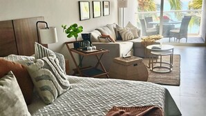 A modern bedroom with a large bed, a sofa, and a dining area. - Beachfront Studio,  New & Cozy,   Stunning Ocean Views,  Prime Location (Puerto Vallarta)