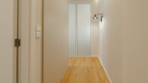 A narrow hallway with wooden flooring, white walls, and a frosted glass door at the end. - Bright Window Apartment by Vacationy (Porto)