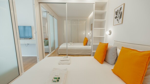 A bedroom with a bed, a bedside table, a TV, a wardrobe, and a shelf with a picture. - Bright Window Apartment by Vacationy (Porto)