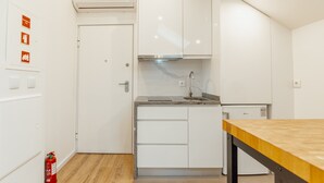A compact kitchen with white cabinets, a built-in oven, and a wooden countertop. - Rooftop Constitui AO by Vacationy (Porto)