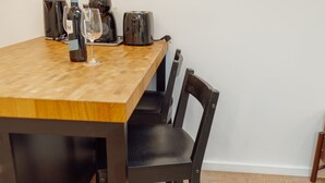 A wooden dining table with a wine bottle and glasses, a toaster, and a coffee maker. - Rooftop Constitui AO by Vacationy (Porto)