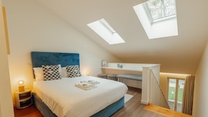 Ein Schlafzimmer mit einem großen Bett, einem Oberlicht, einem Schreibtisch und einer Treppe.