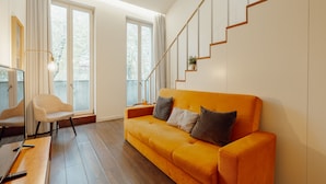 Ein modernes Wohnzimmer mit Holzboden, einer Couch, einem Sessel und einer Treppe.