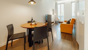 Ein modernes Wohnzimmer mit einem Holzes Esstisch, schwarzen Stühlen, einer Couch und einem Fernseher.