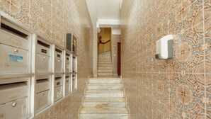 Un couloir aux murs ornés de motifs, un escalier en marbre et un extincteur.