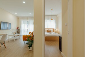 Een moderne hotelkamer met een bed, nachtkastje, lamp en een kamerplant.