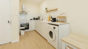 Une cuisine compacte équipée d’un lave-linge, d’un four et d’un petit plan de travail sur lequel sont posés des bocaux.