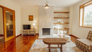 Una sala de estar con chimenea, suelo de madera, un sofá, una mesa de centro y una televisión.