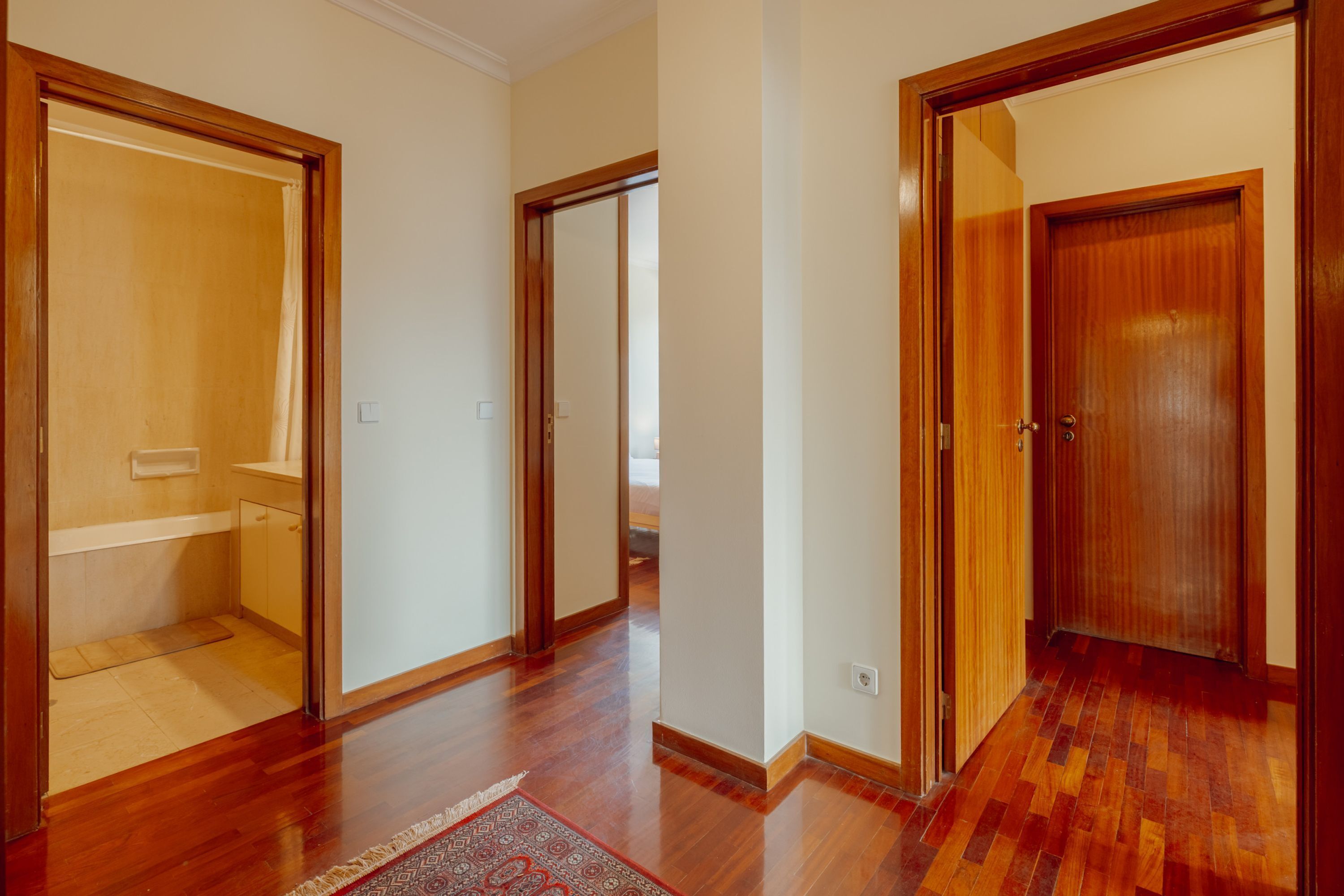 A hallway with wooden flooring and doors leading to different rooms.