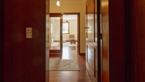 Un pasillo de madera con una alfombra que conduce a una habitación con un banco y un ventanal.