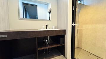 A modern bathroom with a dark vanity, a large mirror, and a glass-enclosed shower.