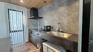 A modern kitchen with a stainless steel sink, a black range hood, and built-in appliances. - The Villa Hotels -SAPPORO- (Sapporo)
