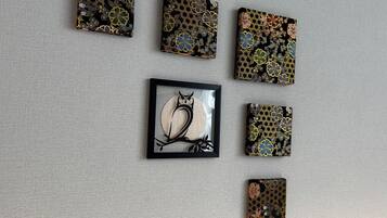 Six œuvres d’art de forme carrée, ornées de motifs floraux, sont disposées sur un mur à texture.