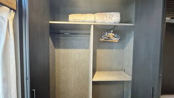 A walk-in closet with a wooden floor, grey walls, and a hanging rack.