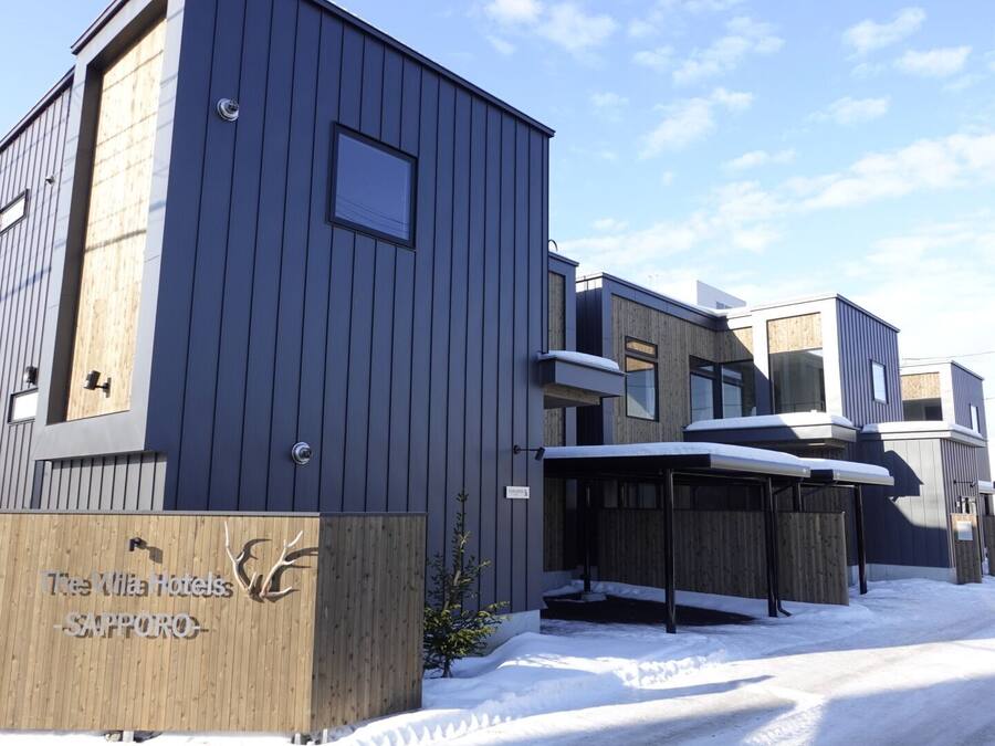 A modern hotel with a wooden facade and a snow-covered entrance.