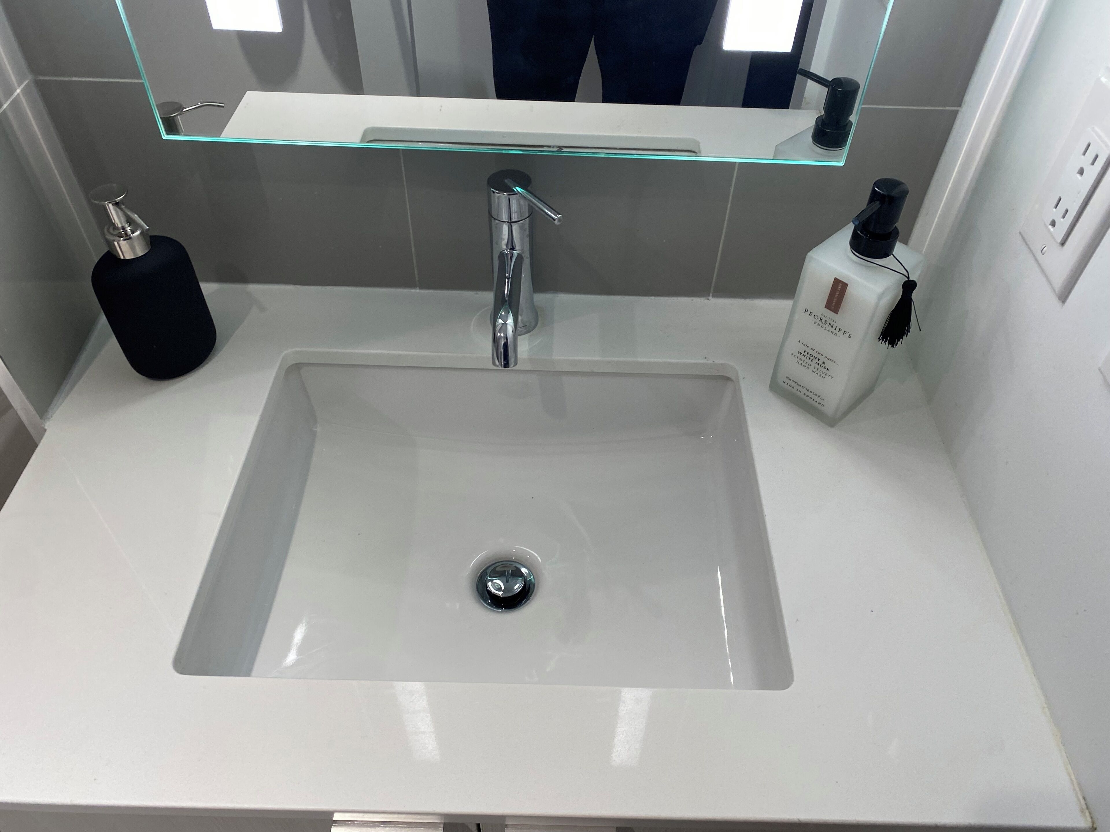 A modern bathroom with a white sink, a glass shelf above the sink, and a mirror.