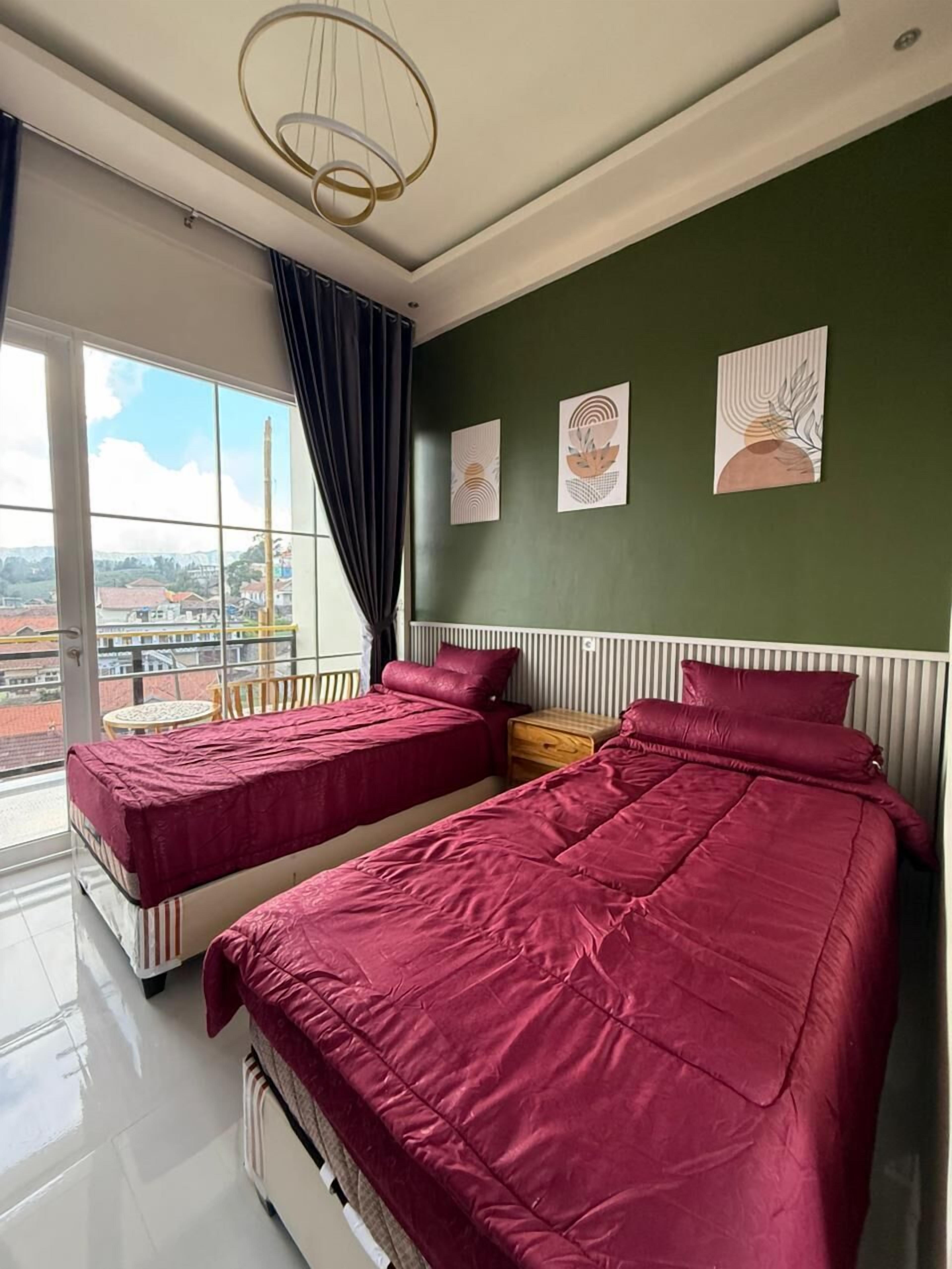 Quarto com duas camas, uma janela grande e obras de arte na parede.