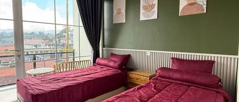 A bedroom with two beds, a large window, and artwork on the wall.
