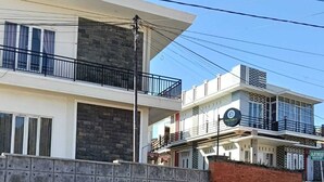 A modern two-story building with a stone wall and a balcony. - Fan Family Bromo Homestay (Ngadisari)