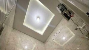 A bathroom with a marble floor, a toilet, a pink bucket, and a ceiling light fixture. - Fan Family Bromo Homestay (Ngadisari)