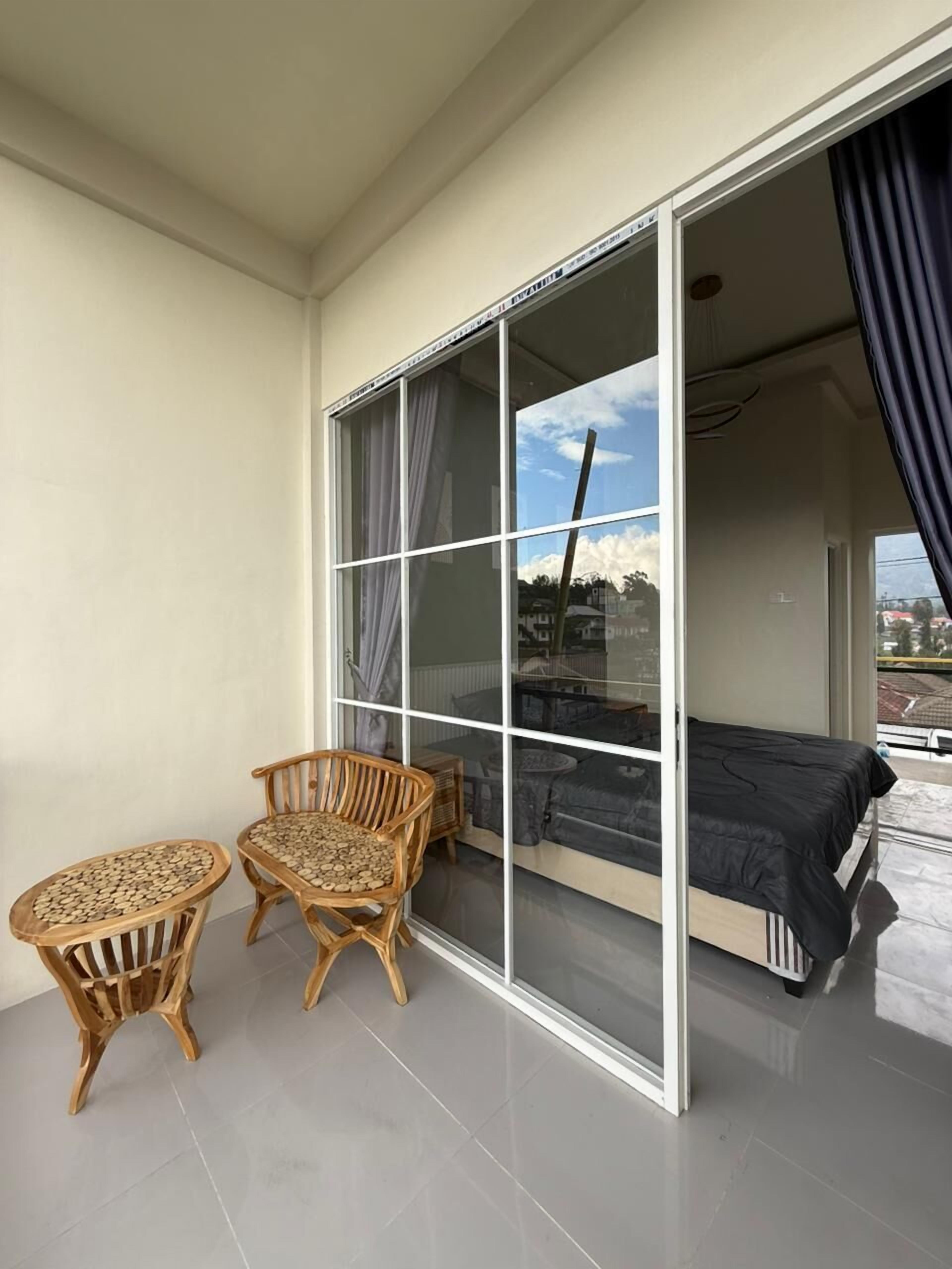 Ein Balkon mit einem Bett, zwei Korbstühlen und einem Tisch.