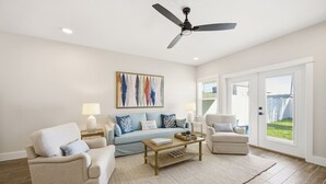 A living room with a sofa, armchairs, a coffee table, and a ceiling fan. - 5-Min Walk to Beach | Good Morning Rentals (Jacksonville Beach)