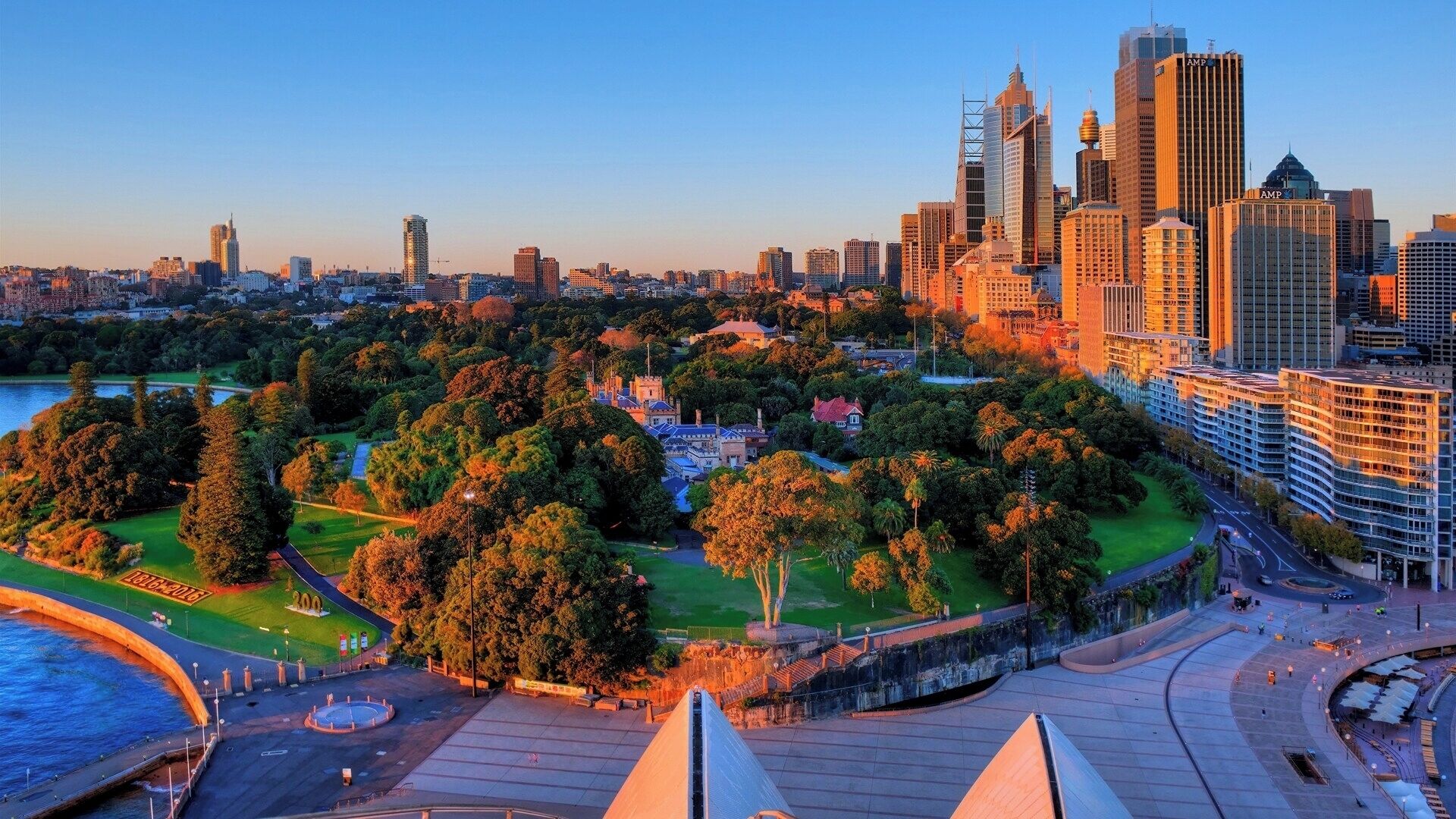 A cityscape with a park, a waterfront, and modern buildings.