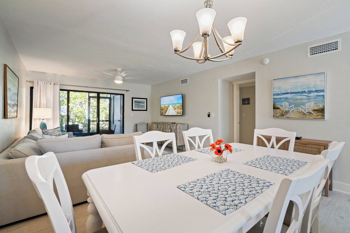 A dining area with a white table, blue placemats, and white chairs.
