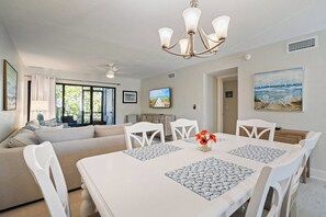 Un área de comedor con una mesa blanca, individuales azules y sillas blancas.