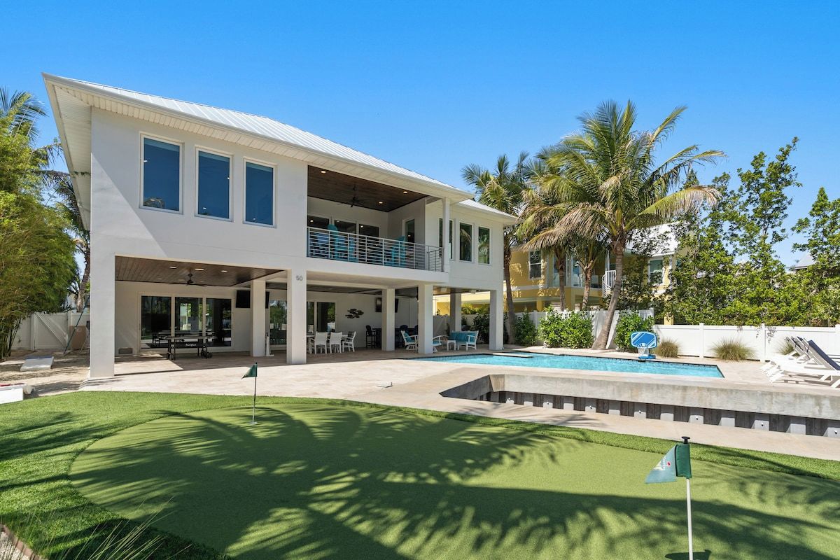 A two-story house with a covered patio, a swimming pool, and a well-maintained lawn.