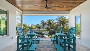 Un espacio de patio techado con techo de madera, sillas color turquesa y piso con estampado de estrella de mar.
