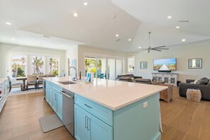 A spacious living area with a large island, a dining area with a table and chairs, and a kitchen with blue cabinets and a large island. - Yacht Sea (Anna Maria)