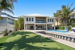 A modern two-story building with a pool, a golf course, and palm trees. - Yacht Sea (Anna Maria)