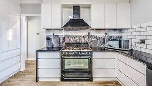 A modern kitchen with white cabinetry, a black stove, and a microwave. - StayAU Pet-Friendly 7Bed Spacious Retreat Morwell (Morwell)