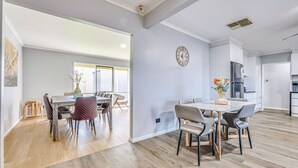A modern apartment with a dining area, kitchen, and a large window. - StayAU Pet-Friendly 7Bed Spacious Retreat Morwell (Morwell)