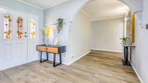 A hallway with wooden flooring, white walls, and a decorative door with stained glass. - StayAU Pet-Friendly 7Bed Spacious Retreat Morwell (Morwell)