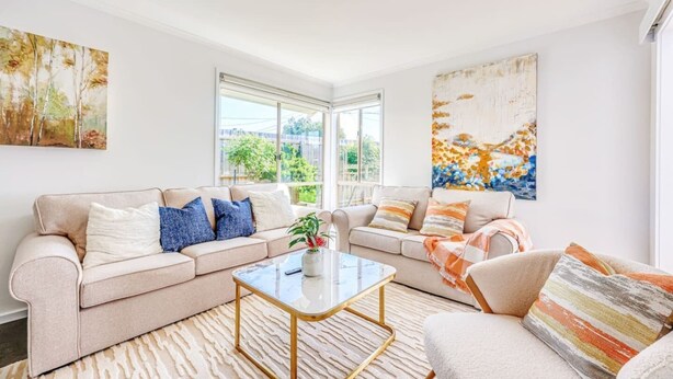 A spacious living room with two sofas, a coffee table, and a large window offering a view of the outdoors.
